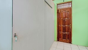A hallway with a wooden door, a green wall, and a tiled floor. - SPOT ON 93592 Pondok Backpackers Ardafa JogjaNearBlue Lagoon Jogja (Ngemplak)