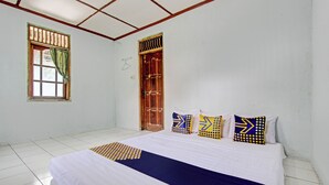 A bedroom with a large bed, a window with curtains, a wooden door, and a tiled floor. - SPOT ON 93592 Pondok Backpackers Ardafa JogjaNearBlue Lagoon Jogja (Ngemplak)