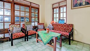 A room with wooden furniture, patterned cushions, and a table with a green tablecloth. - SPOT ON 93592 Pondok Backpackers Ardafa JogjaNearBlue Lagoon Jogja (Ngemplak)
