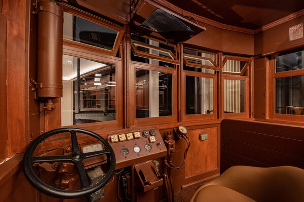 Un panel de control antiguo con indicadores y un volante, paredes de madera y ventanas grandes.