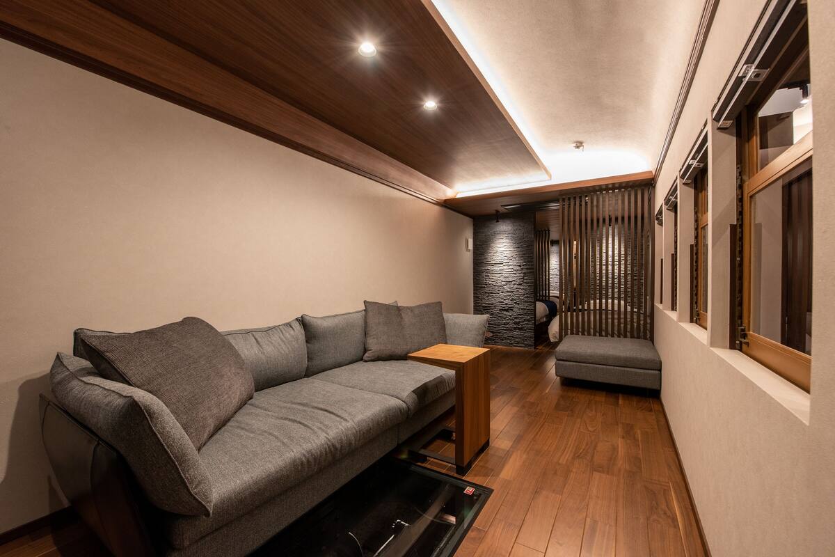 A modern living room with a grey sofa, a wooden coffee table, and a stone accent wall.