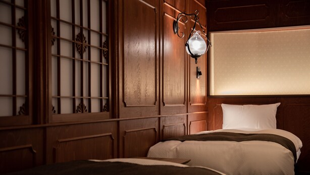 Ein Hotelzimmer mit zwei Betten, Holzwandverkleidung und einer Wandleuchte.