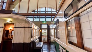A train interior with a bench seating area, a small table, and a window providing a view of the outside. - Kisyapoppo (Nakatsu)