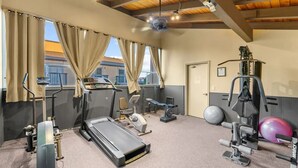 A gym with exercise equipment, a treadmill, and a ceiling fan.