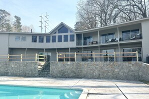 A two-story building with a stone retaining wall, a swimming pool, and a balcony with a railing. - Great for Traveling Work Teams /20-30 minutes to downtown Atlanta/Sleeps 12/Private Pool (Jonesboro)