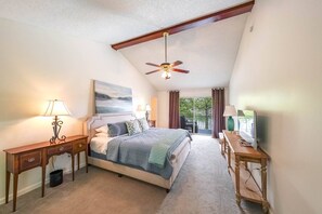 A bedroom with a bed, two bedside tables, a ceiling fan, a painting, and a view of the outdoors. - Great for Traveling Work Teams /20-30 minutes to downtown Atlanta/Sleeps 12/Private Pool (Jonesboro)