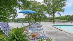 A poolside area with lounge chairs, a blue umbrella, and a view of a lake. - Great for Traveling Work Teams /20-30 minutes to downtown Atlanta/Sleeps 12/Private Pool (Jonesboro)