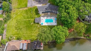 An aerial view of a property with a swimming pool, dock, and surrounding greenery. - Great for Traveling Work Teams /20-30 minutes to downtown Atlanta/Sleeps 12/Private Pool (Jonesboro)