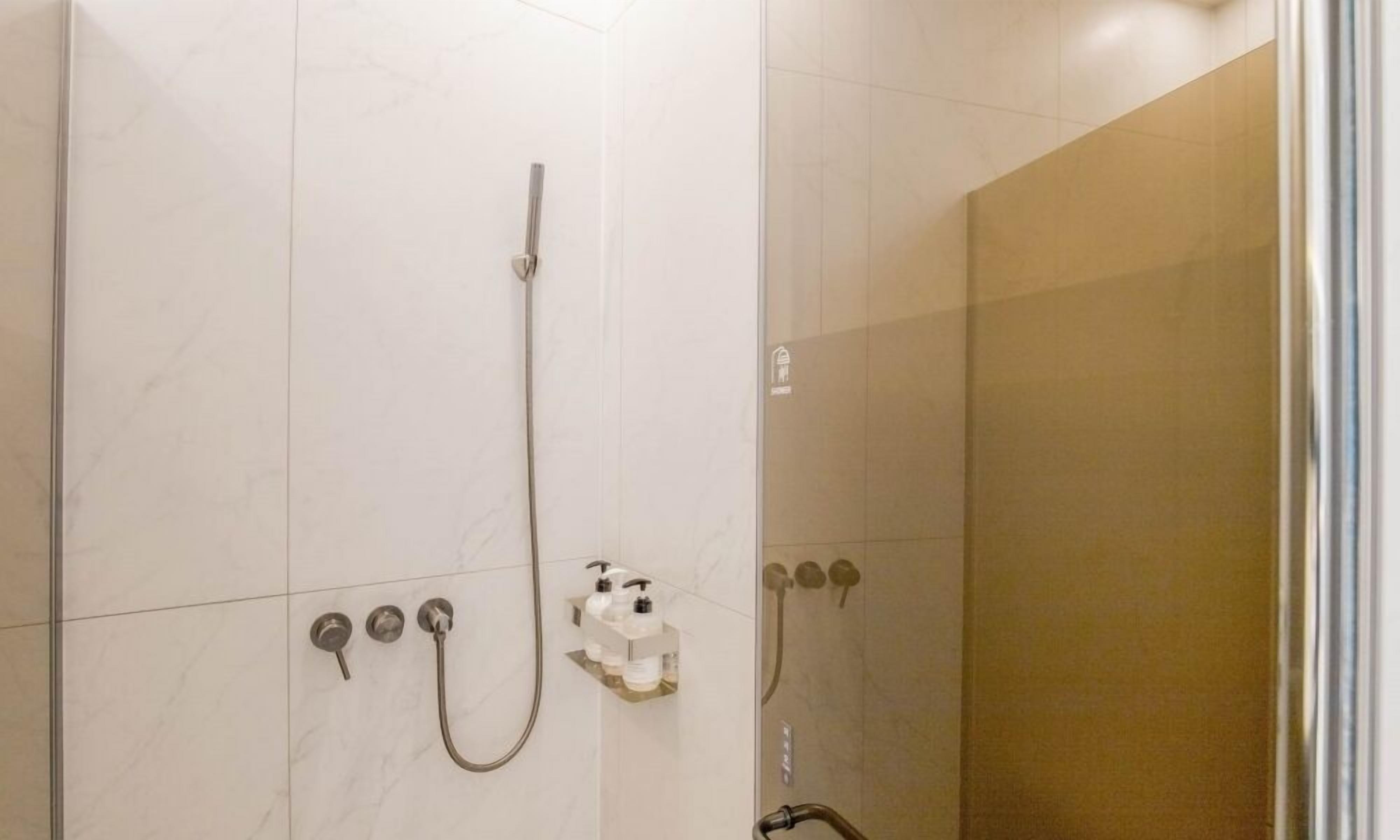Une douche moderne dotée d’une paroi en verre, d’un pommeau de douche à main et d’un robinet mural.