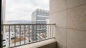 Un balcón con barandilla de metal que da a un paisaje urbano con edificios modernos y una montaña al fondo.