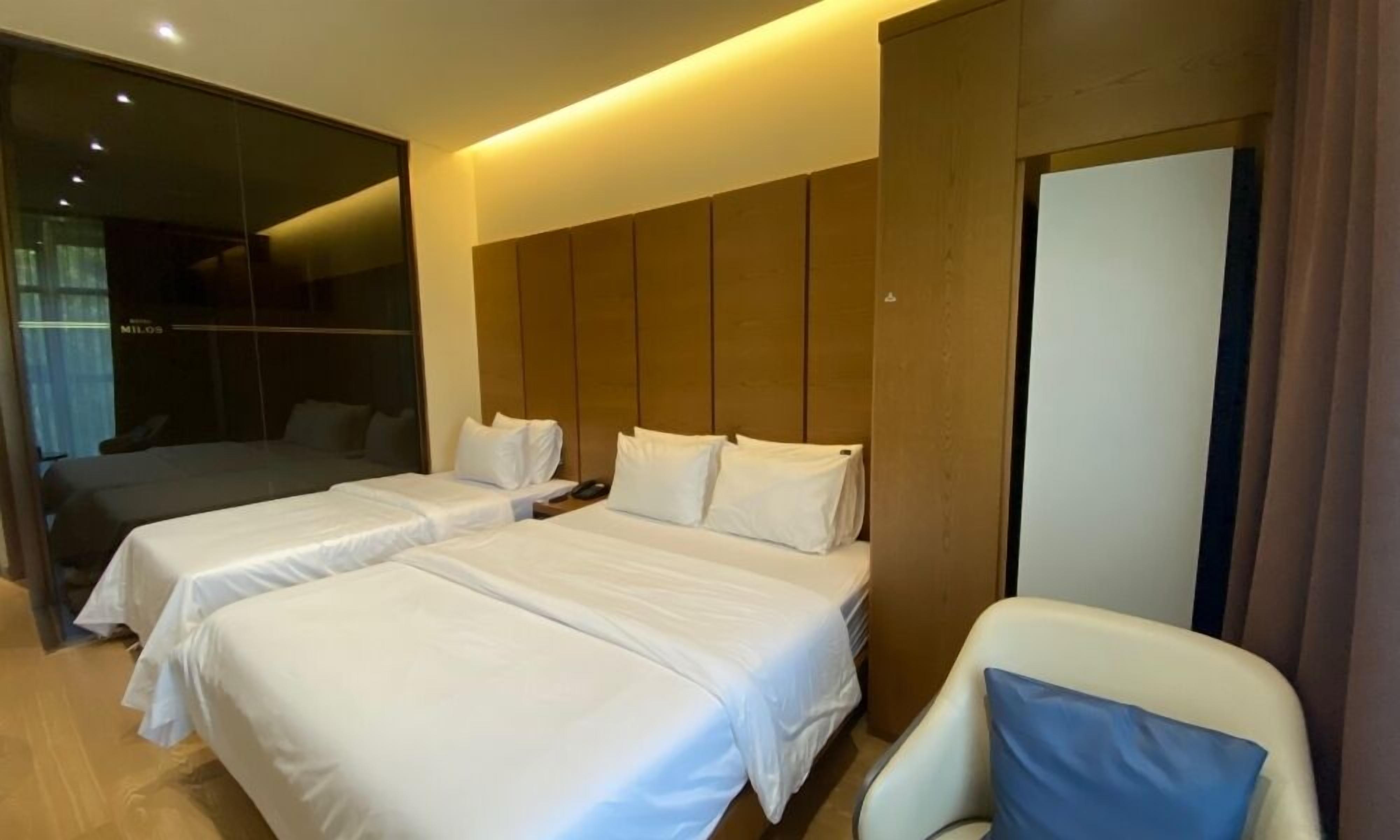 Une chambre d’hôtel avec deux lits, un grand miroir et un coin salon.