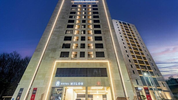 Un hotel de varios pisos con una entrada destacada y señalización iluminada.