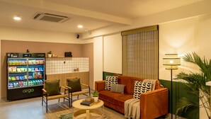Uma sala de estar moderna com sofá, cadeiras, mesa de centro e máquina de venda automática de lanches.