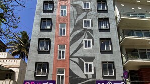 Um edifício de vários andares com uma grande janela no andar térreo, um letreiro de 'zip' ao vivo e um letreiro de estacionamento 'P'.