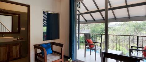 A room with a balcony, a sofa, a table, and a window.