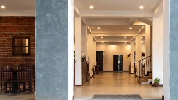 Un hall d’entrée spacieux, avec un mur en briques d’un côté et un intérieur moderne de l’autre.