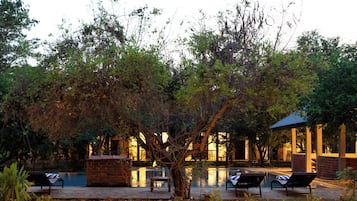 A serene outdoor area with a swimming pool, lounge chairs, and a gazebo.