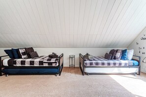 A bedroom with two beds, a small table, and a wall with decorative elements.