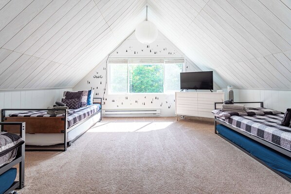 Habitación tipo dormitorio con literas, televisor, calefacción y ventana con vistas a árboles.