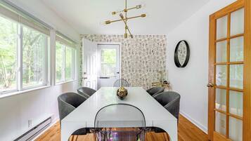 A dining area with a white table, four chairs, a chandelier, and a patterned wallpaper.
