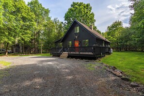 Een zwarte cabin met een rode deur, een terras en een decoratie van een hertenkop.