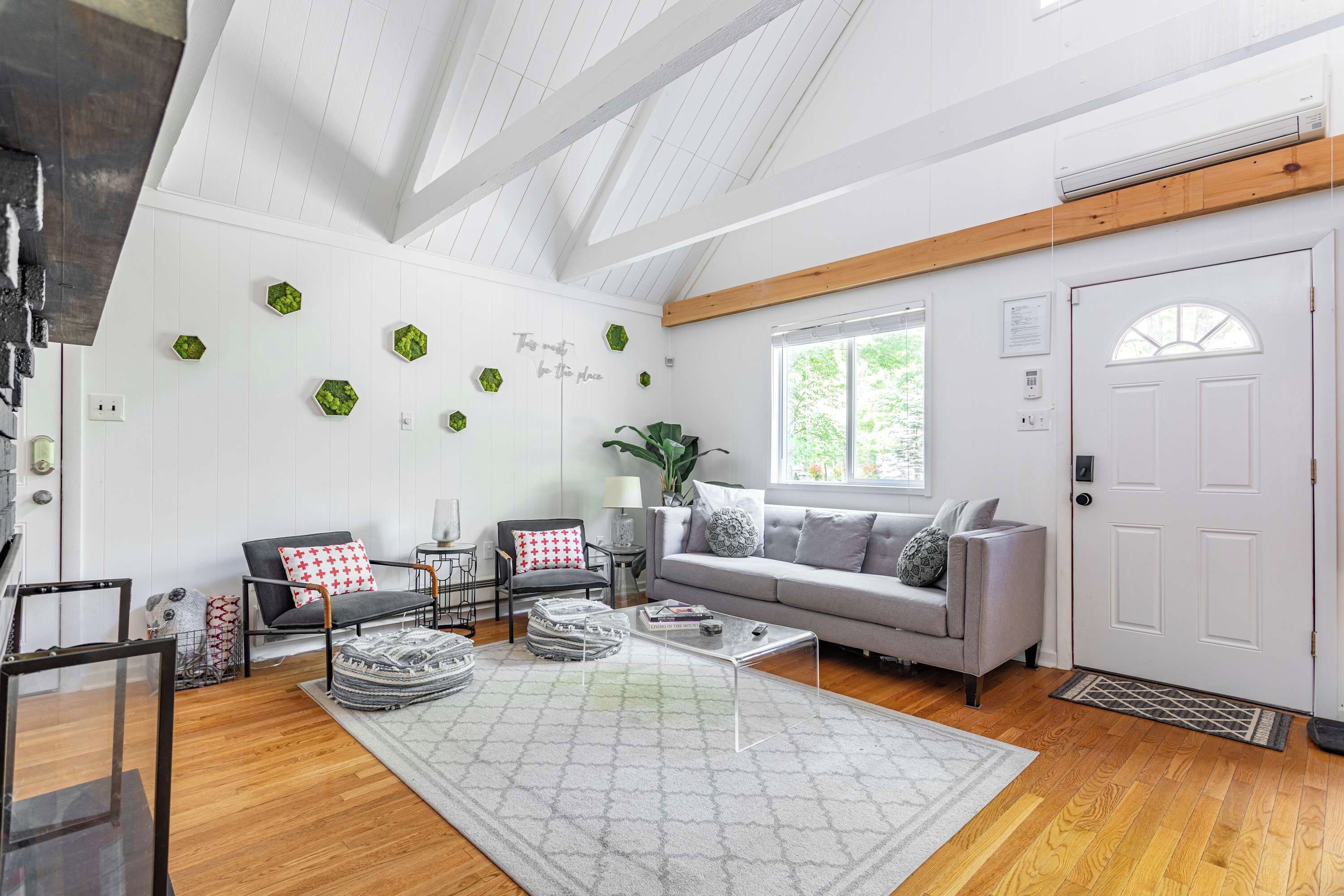 A modern living room with a wooden ceiling, a grey sofa, a coffee table, and a large rug.