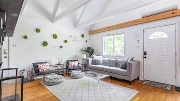 A modern living room with a wooden ceiling, a grey sofa, a coffee table, and a large rug.