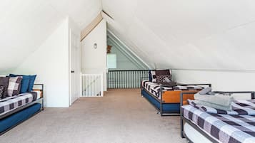 Een kamer in een studentencomplex met stapelbedden, een trap en een wit plafond.
