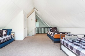 Een kamer in een studentencomplex met stapelbedden, een trap en een wit plafond.
