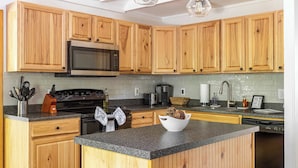 A kitchen with wooden cabinets, a granite countertop, a microwave, an oven, and a sink. - Stag Chalet: Summer Retreat | 3BD | Pet Friendly (Albrightsville)