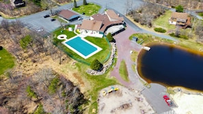 Vista aérea de una zona residencial con piscina, un estanque grande y un estacionamiento.
