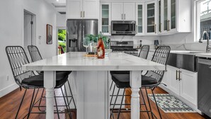 Una cocina moderna con armarios blancos, electrodomésticos de acero inoxidable y una isla central con sillas.