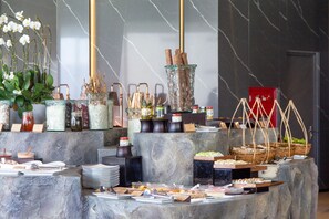 A buffet setup with various food items, jars of condiments, and a potted plant. - M HOTEL DANANG (Da Nang)