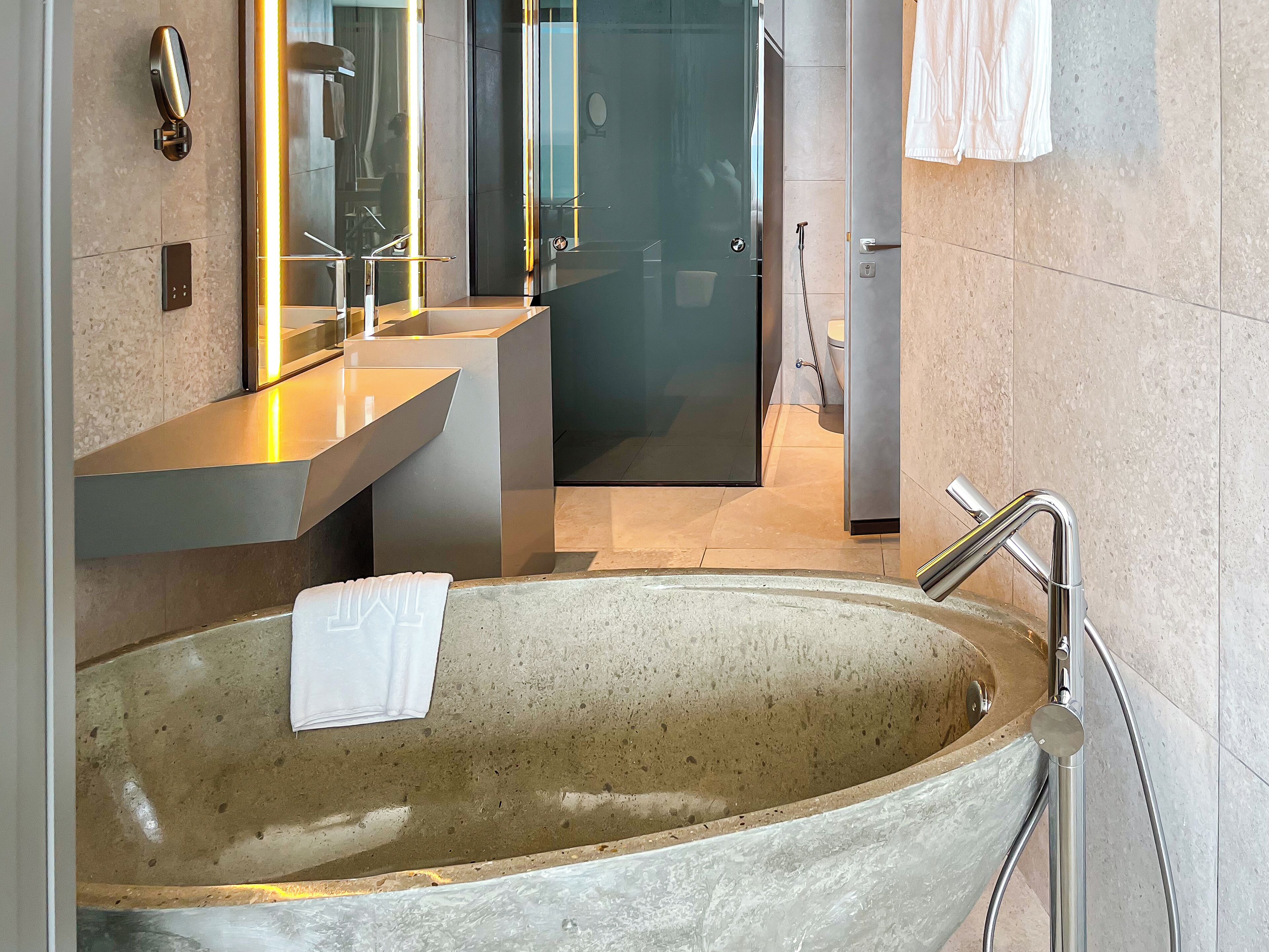 Une salle de bain moderne avec une grande baignoire sur pieds, deux vasques avec miroirs et une douche à l’italienne en verre.