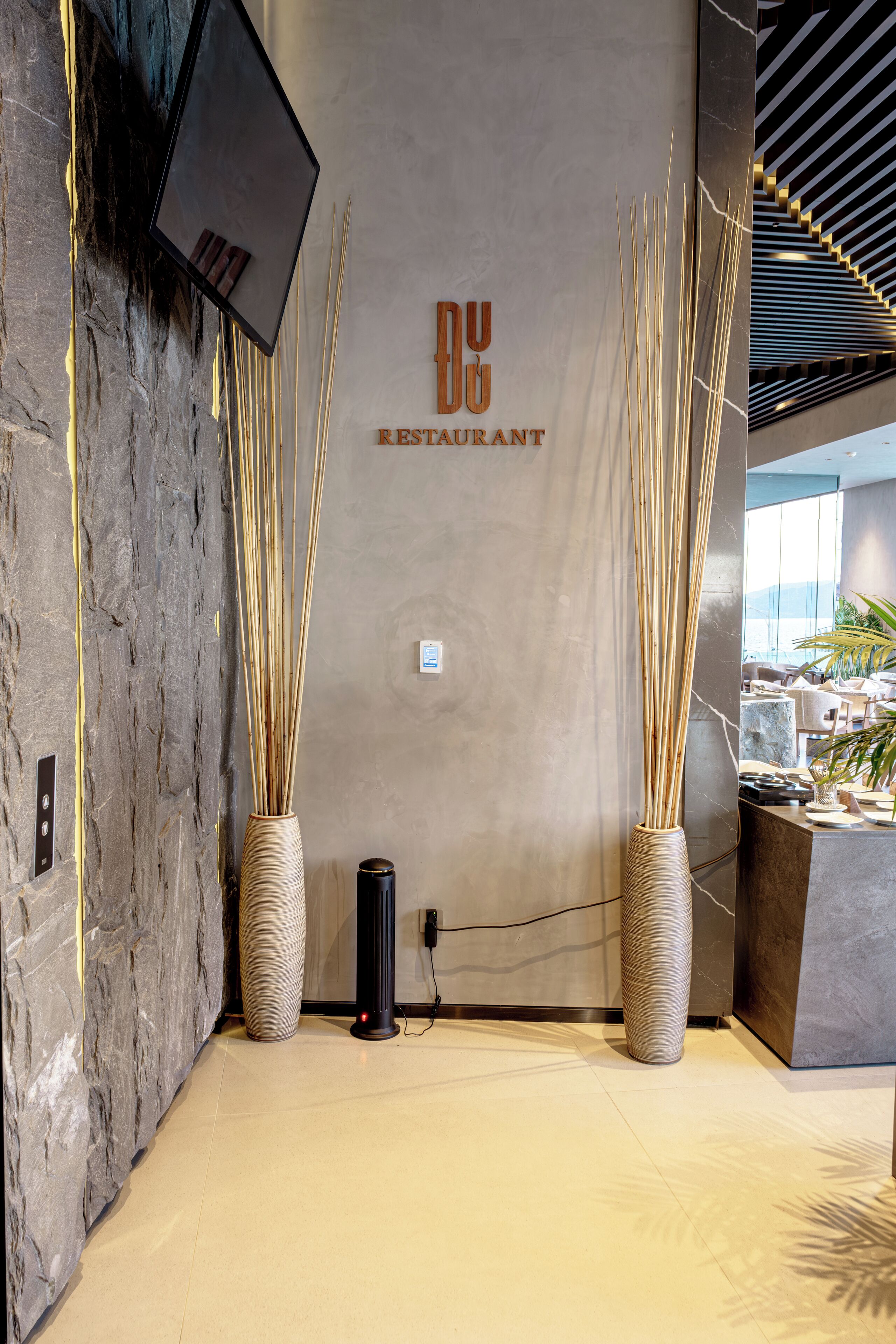 A modern interior with a stone wall, two tall vases, and a sign reading "DUO RESTAURANT".