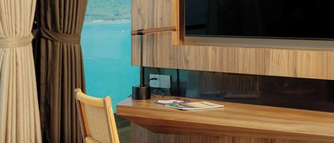 Una habitación moderna con un escritorio de madera, una silla, un televisor de pantalla plana y vistas al mar.