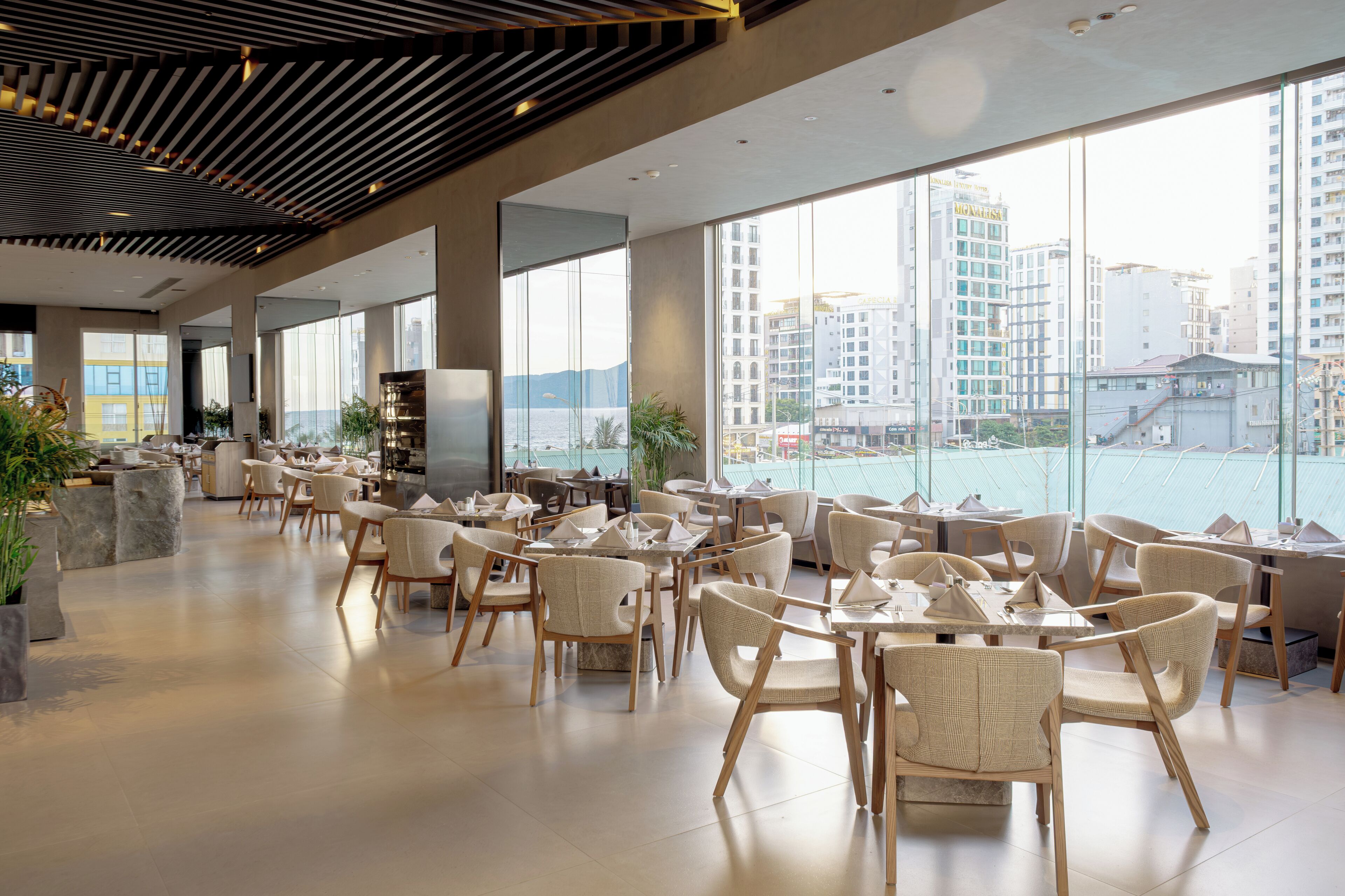 En modern restaurang med högt i tak, stora fönster och utsikt över staden.