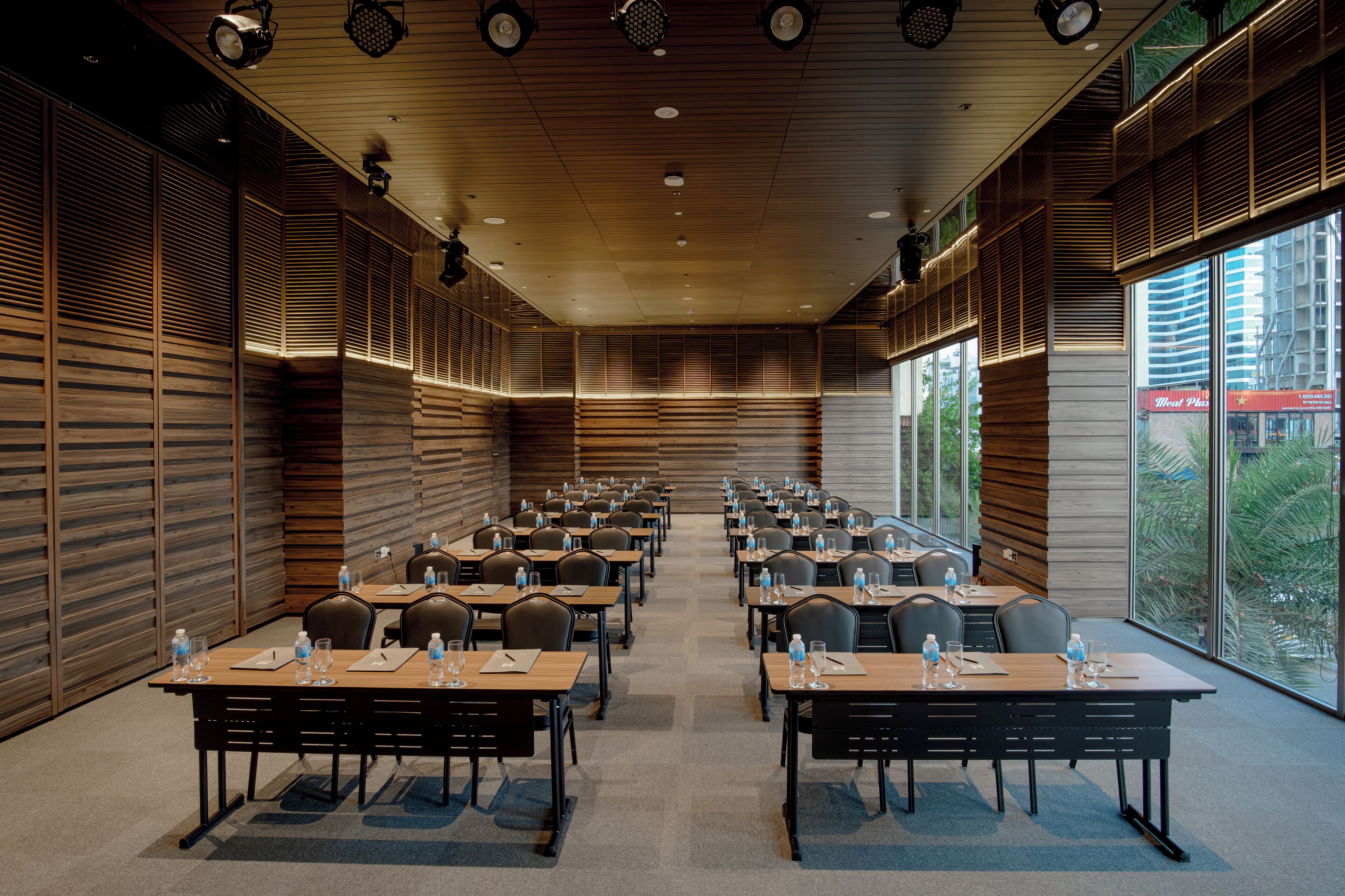 A conference room with multiple tables and chairs, equipped with water bottles and notepads.