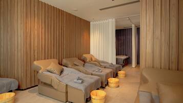 Un cuarto de spa con tres camillas de masaje, paredes de madera y un ventanal con cortinas.