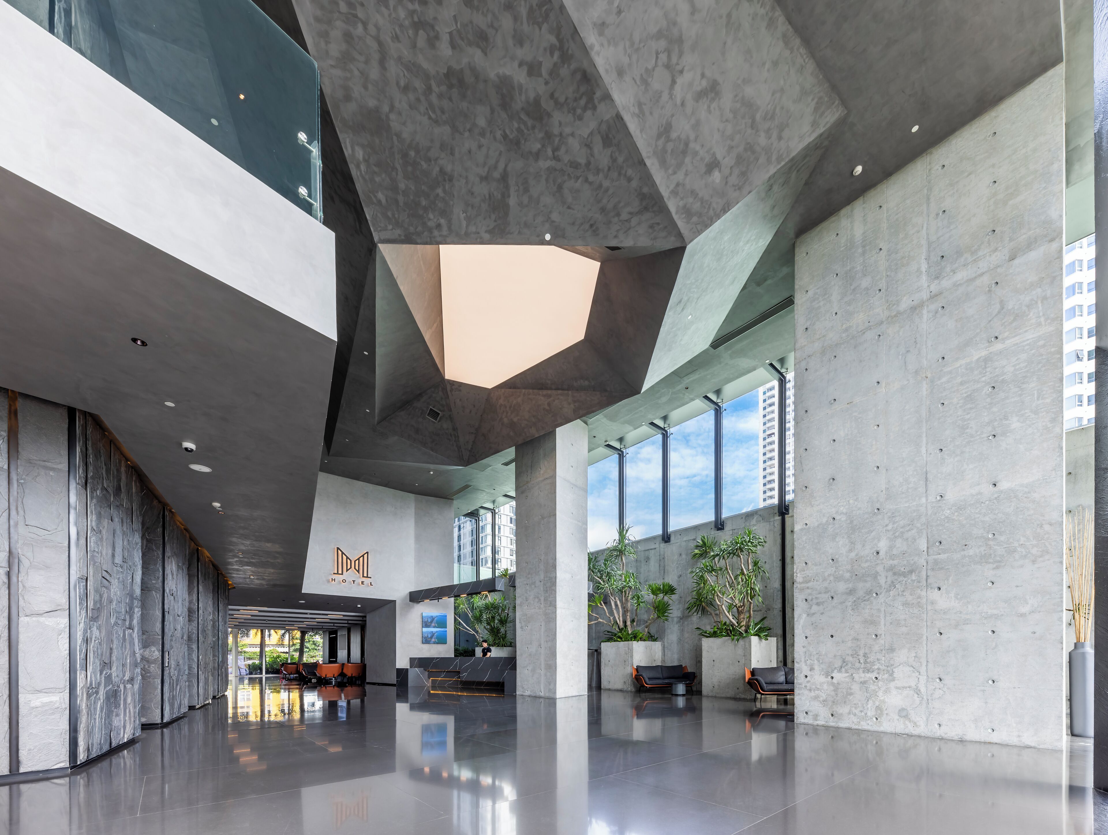 Un hall d’entrée spacieux au design moderne, comprenant un comptoir d’accueil, un espace salon et de grandes fenêtres.