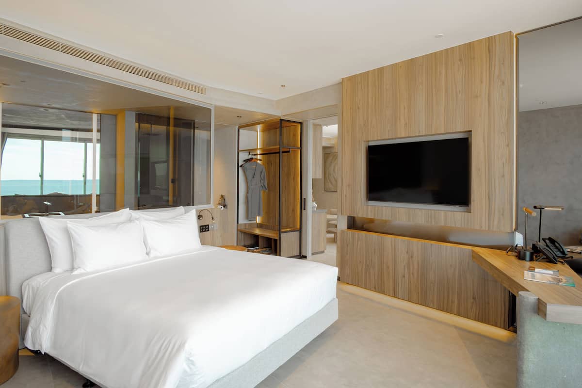A modern hotel room with a large bed, a TV mounted on the wall, and a wooden panel design.