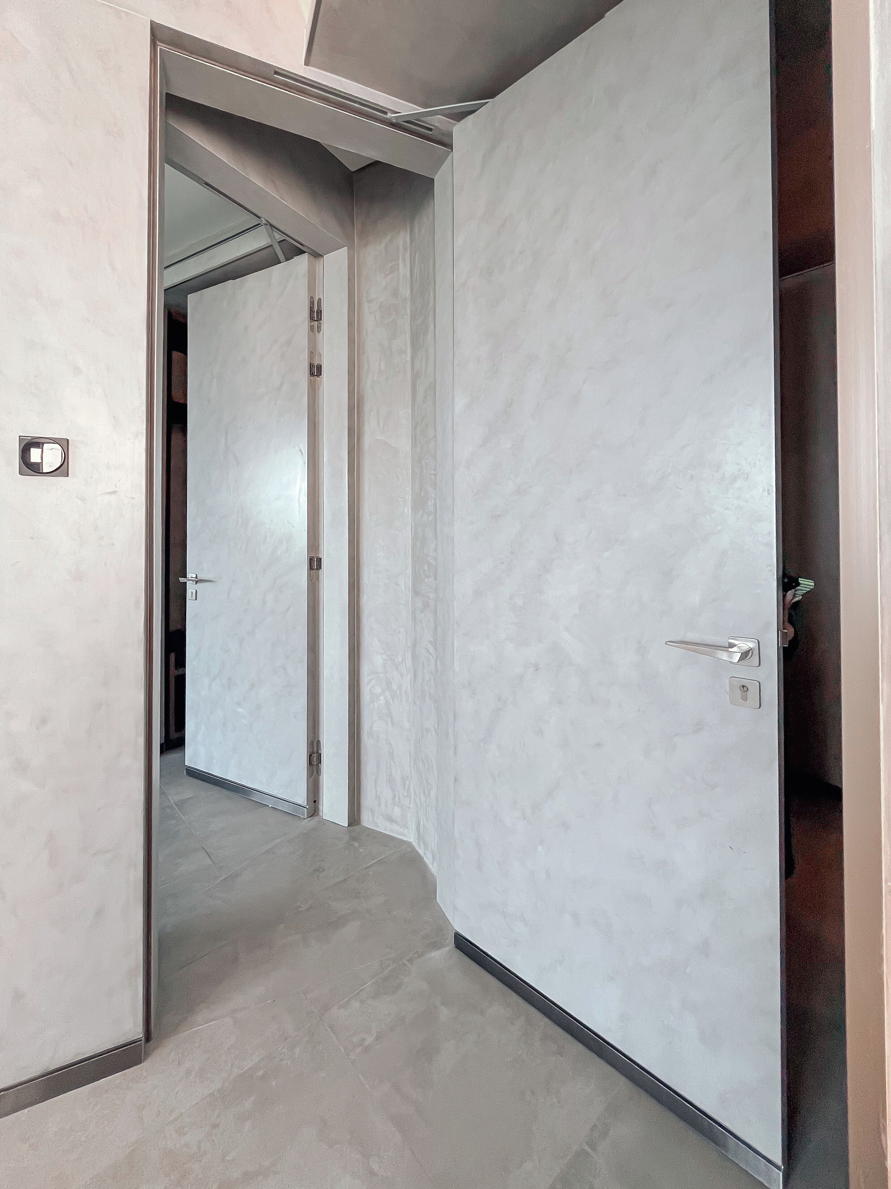 Un pasillo con una pared de mármol y una puerta que da a otra habitación.