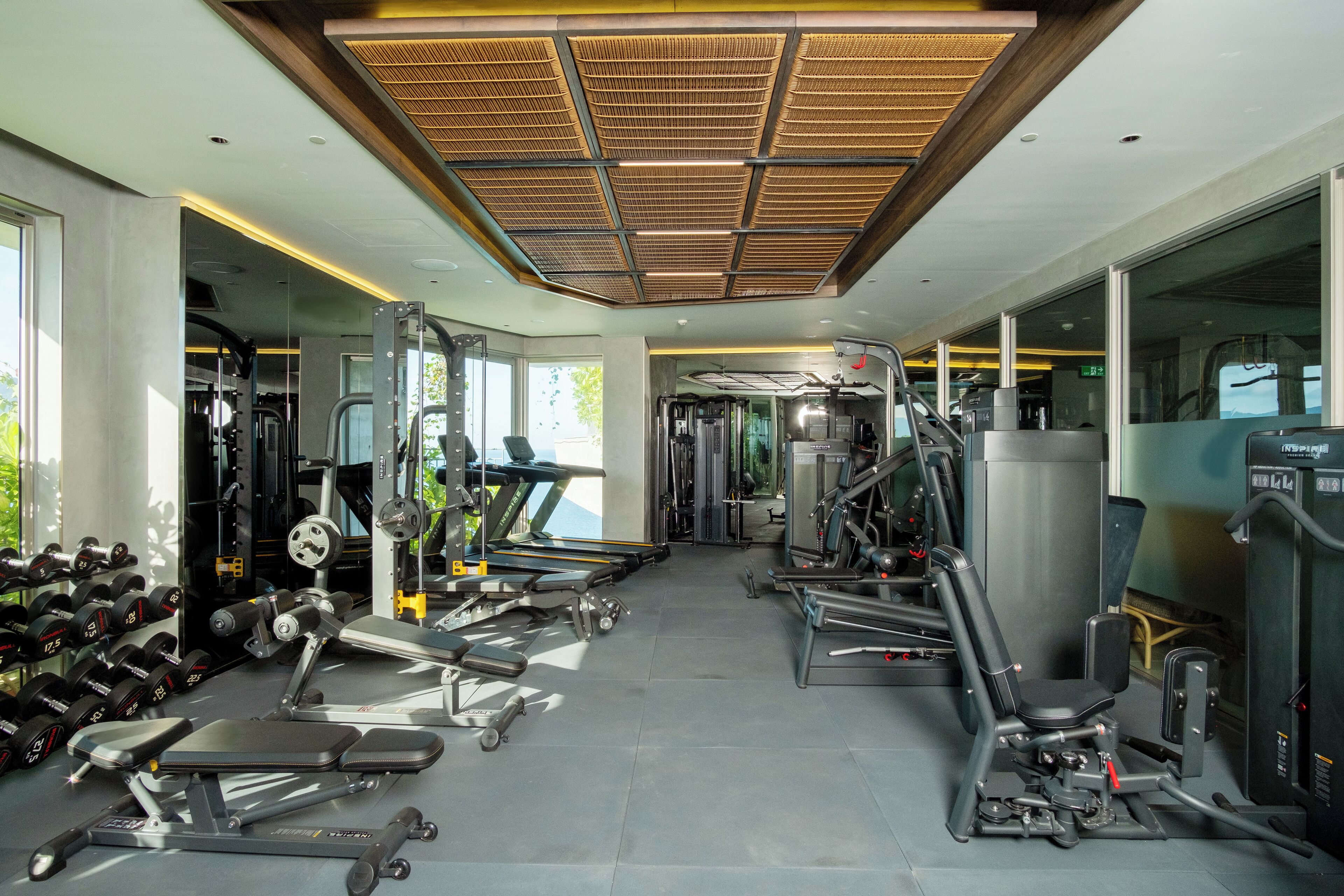 A gym with various exercise equipment, a treadmill, and dumbbells.