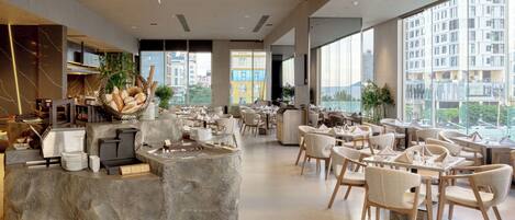 Un café moderne avec un comptoir en pierre, des sièges confortables et de grandes fenêtres offrant une vue sur la ville.