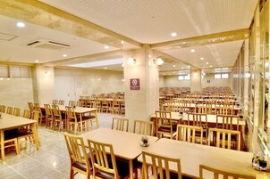 A large dining hall with multiple tables and chairs, a no-smoking sign, and a tiled floor.