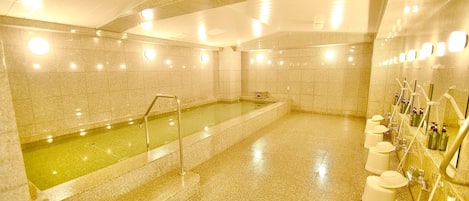 A spa area with a hot tub, tiled walls, and a row of toiletries on the right.