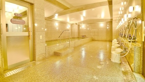 Zona de spa con bañera de hidromasaje, entrada con puerta de vidrio y varios lavamanos con dispensadores de jabón.