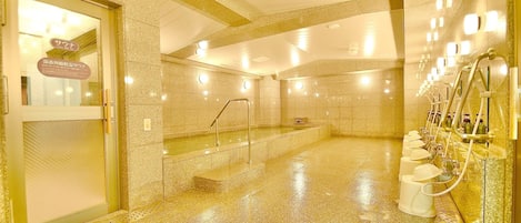 Een wellnessruimte met een jacuzzi, een glazen deur en een rij wastafels met zeepdispensers.