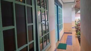 A corridor with a tiled floor, a green mat, and a door with a blue frame. - SPOT ON 93596 Pondok Wisata Pesona Asri (Pleret)