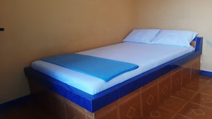 A single bed with a blue headboard and white bedding in a room with plain walls and patterned floor tiles. - SPOT ON 93596 Pondok Wisata Pesona Asri (Pleret)